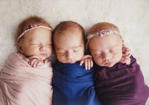 Three newborns wrapped in blankets